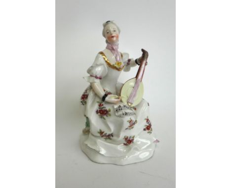 A Vienna figure of a lady playing a mandolin, circa 1770, blue shield mark, modelled with sheet music on her knee, on a natur