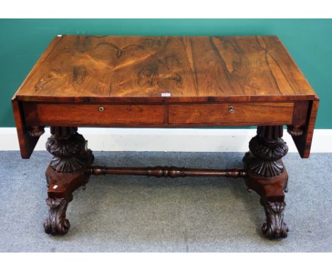 A late George III rosewood sofa table, the drop flap top over pair of frieze drawers, on carved and reeded columns and acanth