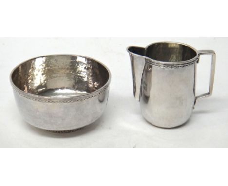 A silver sugar basin, with a matching milk jug, each having decorated borders, otherwise with martele decoration, London 1928