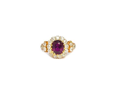 A gold, ruby and diamond oval cluster ring, claw set with the oval cut ruby at the centre, within a surround of thirteen cush