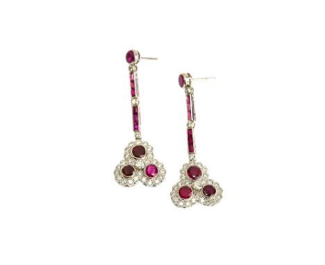 A pair of ruby and diamond set triple cluster earrings, each with a millegrain set solitaire ruby surmount above two rows of 