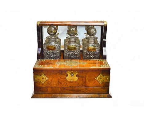 A Victorian brass mounted figured walnut decanter box/games compendium, with a trio of decanters over pair of lift-up tops an