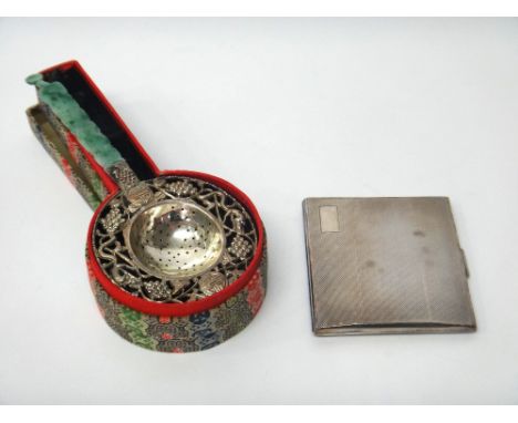 A Chinese tea strainer, the border pierced and embossed with leaves, berries and animals and with a carved jade handle, with 