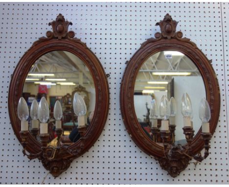 A pair of Victorian oval three light girandole wall mirrors, with cartouche carved crest, 48cm wide x 80cm high, (2).