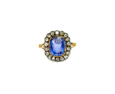 A diamond and sapphire intaglio cluster ring, mounted with the cushion shaped sapphire intaglio to the centre, carved as the 