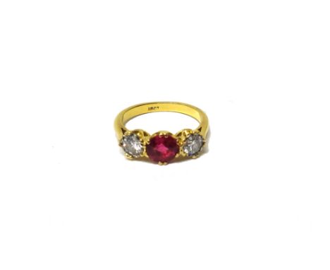 A gold, synthetic ruby and diamond set three stone ring, claw set with the circular cut synthetic ruby at the centre, between