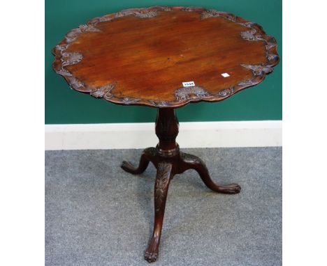 A George III style mahogany occasional table, the carved and shaped top on birdcage support, tripod base and ball and claw fe