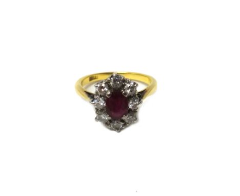 A gold, ruby and diamond set nine stone oval cluster ring, claw set with the oval cut ruby at the centre, in a surround of ei