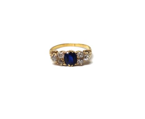 A gold, sapphire and diamond ring, mounted with the oval cut sapphire to the centre, between cushion shaped diamond set three