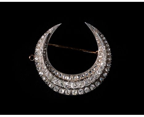 A Victorian diamond brooch, designed as a crescent, mounted with a row of graduated cushion shaped diamonds to the centre, in
