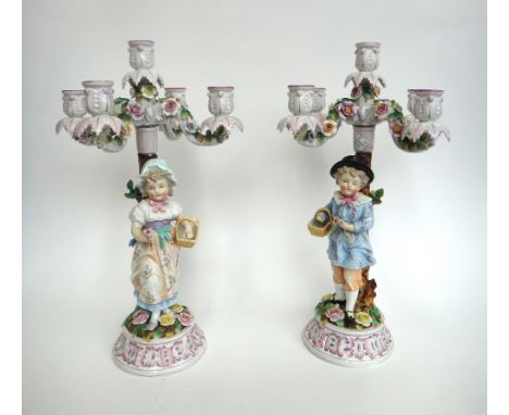 A pair of Sitzendorf porcelain five-light candelabra, late 19th century, modelled as a young boy and girl standing below four