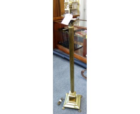 A brass standard lamp formed as a reeded Corinthian column, on a square stepped base with paw feet, 123cm high excluding fitm