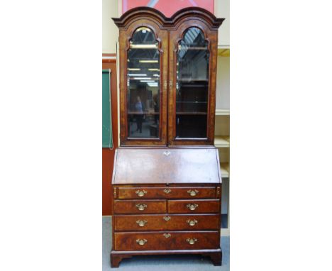 A George II figured walnut bureau bookcase, the double domed top over a pair of bevelled glazed arch top doors, the fall with