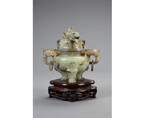 A CHINESE CARVED JADE TRIPOD CENSER, 20TH CENTURY. With animal form ring handles and dragon finial cover, on a fitted carved 