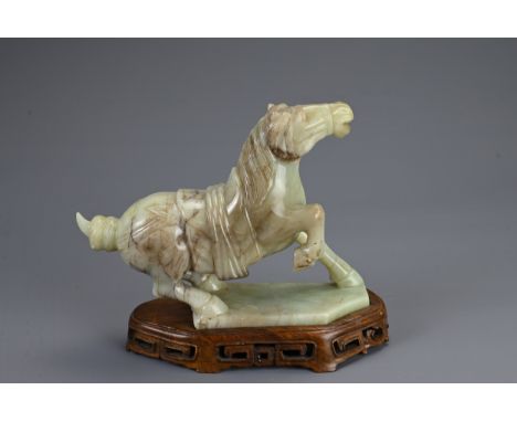 A CHINESE CARVED JADE MODEL OF A PRANCING HORSE, 20TH CENTURY. Mounted on a carved and pierced wooden stand. 24cm length.Very
