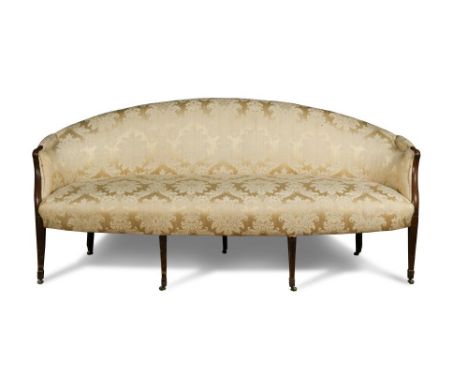 A George III mahogany sofa, with an arched back, show wood arms and upholstered in a damask fabric, on tapering fluted column