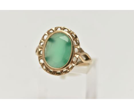 A 9CT GOLD GREEN CHALCEDONY RING, of an oval form, collet set within an openwork surround, trifurcated shoulders leading onto