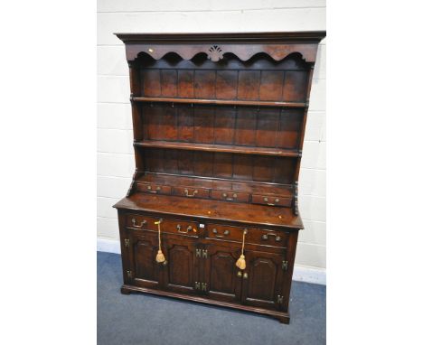 A TITCHMARSH AND GOODWIN STYLE OAK DRESSER, the top with a wavy apron, two shelves and four drawers, over a base with two dra