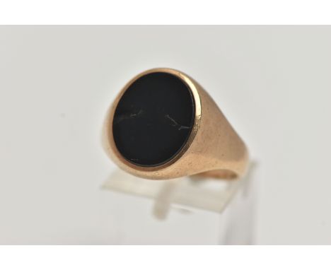 A GENTS 9CT GOLD ONYX SIGNET RING, of an oval design set with a polished onyx inlay (two cracks), to a polished tapered band,