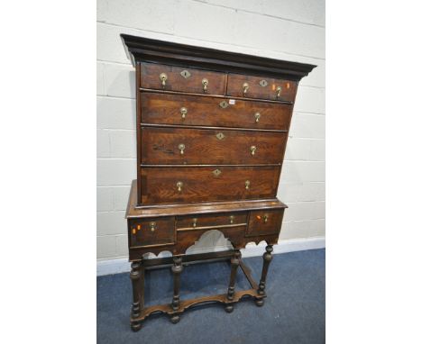 A PART QUEEN ANNE OAK AND CROSSBANDED CHEST ON STAND, with a fixed overhanging cornice, two short over three long graduated d
