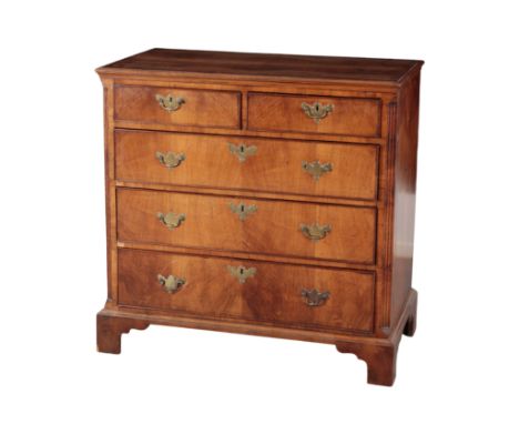 A GEORGE III WALNUT CHEST OF DRAWERS with a crossbanded top, over two short and three long drawers, and canted fluted corners