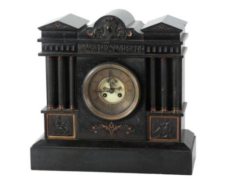 A LATE VICTORIAN SLATE MANTEL CLOCK the architectural case with a relief carved frieze over the brass dial, flanked by sets o