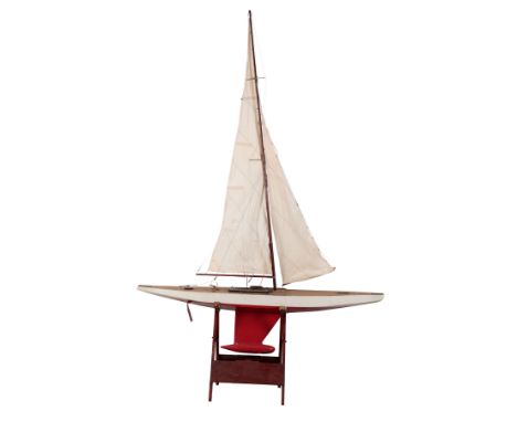 AN EARLY 20TH CENTURY 10 R CLASS POND YACHT AND STAND rigged with mainsail and jib, over a simulated plank deck, the yacht is