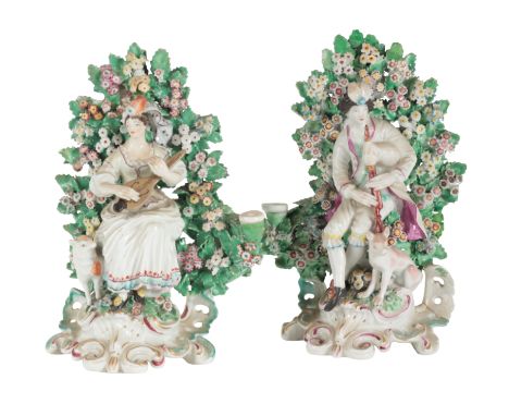 A PAIR OF 18TH CENTURY DUESBURY &amp; CO DERBY PORCELAIN CANDLESTICKS modelled with seated shepherd and shepherdess within bo