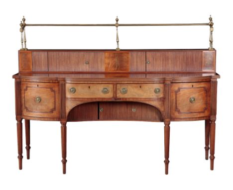 A GEORGE III MAHOGANY AND BRASS MOUNTED SIDEBOARD IN THE MANNER OF GILLOWS the brass gallery with urn finials, over a tambour