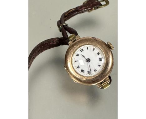 A Vintage 1930s lady's 9ct gold cased wristwatch with white enamel dial and roman numerals on leather thong strap, with engra