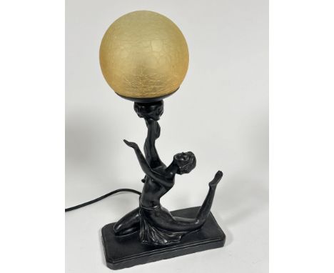 A reproduction Art Deco style lamp with seated dancer with arms upraised holding a golden craquelure glass globe on rectangul