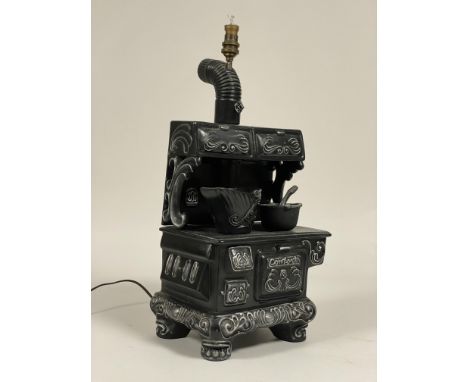 An unusual ceramic table lamp in the form of a 19th century stove, complete with cooking pot, ladle and coal scuttle, the scu