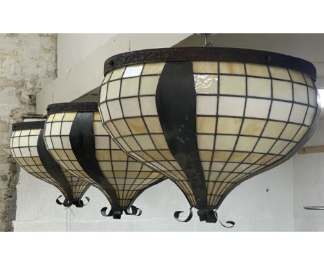 A set of three large lead glazed slag glass pendent light fittings of compressed form, with floral hammered copper mounts. D7