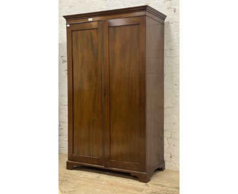 An Early 20th century mahogany wardrobe, the projecting cornice above two panelled doors enclosing a shelf and hanging rail, 