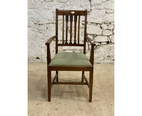 An Arts and Crafts period walnut, mahogany and beech elbow chair, with carved crest rail and spars above a drop in upholstere