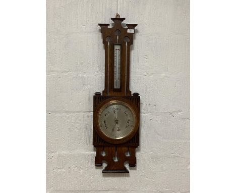 An Arts and Crafts pierce carved oak framed wall hanging aneroid barometer and thermometer, early 20th century, with silvered