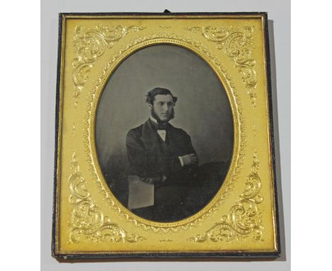 A mid 19th Century ambrotype depicting a young gentleman stood with arms crossed and holding a piece of paper, gilt oval moun