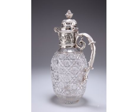 A SILVER-PLATE MOUNTED CUT-GLASS CLARET JUG, the hinged domed cover with basket of fruit finial and chased with scrolls and f