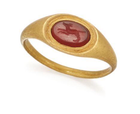 A ROMAN CARNELIAN INTAGLIO RING, an oval carnelian carved with a hound, in running pose with forelegs extended, within a step