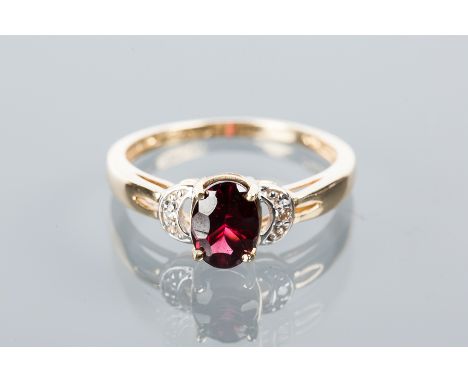 GARNET AND DIAMOND RING
with a central oval brilliant cut garnet measuring 7.48mm flanked by two brillient cut brilliant cut 