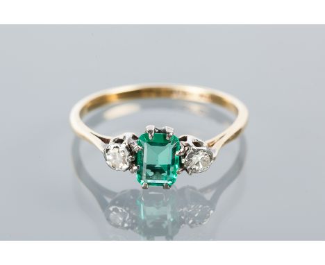 EMERALD AND DIAMOND THREE STONE RING
with a central step cut emerald of approximately 0.61 carats, flanked by brilliant cut d