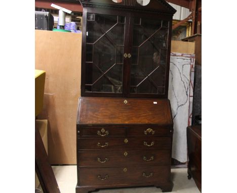 A George III mahogany bureau bookcase, the upper section surmounted by an architectural broken arch pediment above adjustable