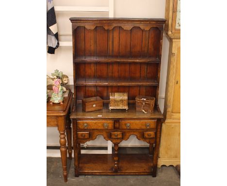 An oak dresser, of small proportions, having shelved and boarded plate rack, fitted three spice drawers and two larger drawer