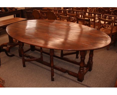 A large good quality oak gate leg dining table, in the 18th Century style, rounded drop leaves raised on baluster turned supp