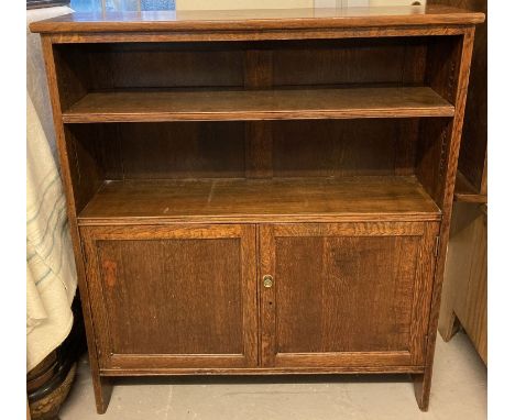 A vintage solid dark oak bookcase with 2 door cupboard and interior shelf.  Upper shelf adjustable.  Approx. 107 x 94 x 26cm.