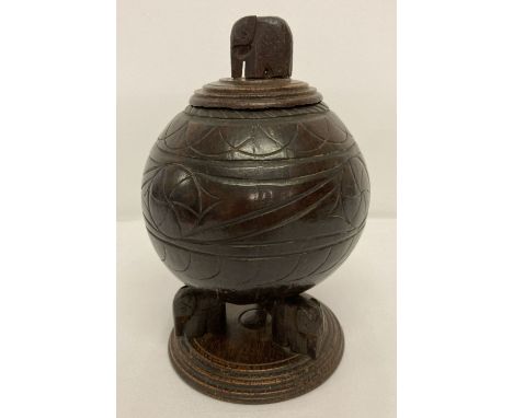 A vintage carved coconut shell canister/tea caddy raised on wooden tripod base with elephant feet.  Carved wooden lid with el