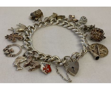 A vintage silver charm bracelet with padlock, safety chain and 16 silver and white metal charms.  Hallmarked London 1978. Cha