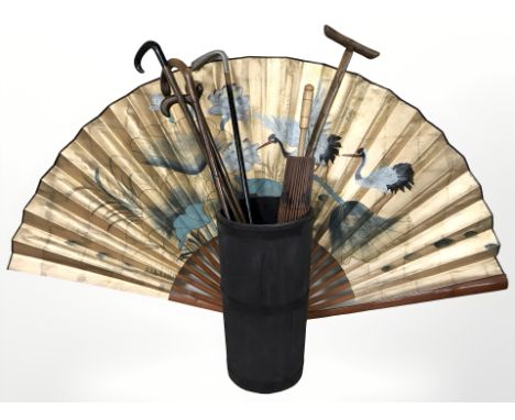 A metal bound stick pot containing walking sticks, parasol, a large oriental fan, etc. 