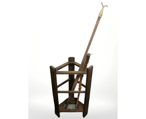 An Edwardian oak stick stand containing two walking sticks and a window pull.
