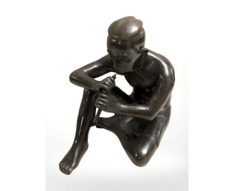 A hollow cast and patinated bronze figure of a seated man playing a flute, height 27.5 cm.